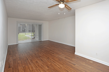 Brown hardwood like flooring in large open white room with a brown ceiling fan.